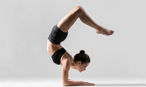 Woman doing scorpion handstand pose