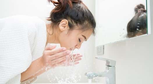 Image of a woman washing her face.