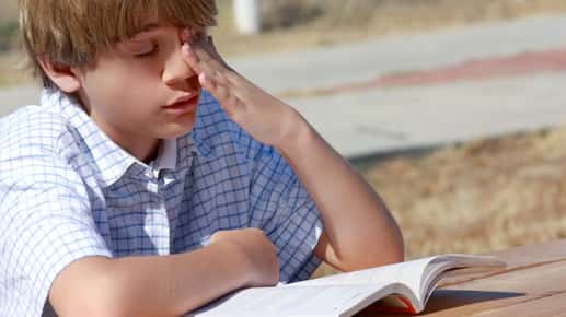 teen rubs left eye while reading
