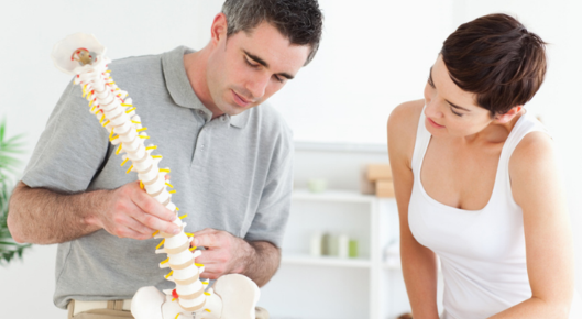 Chiropractor with patient looking at model spine
