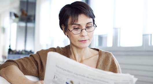 Image of a child reading in bed wearing glasses.