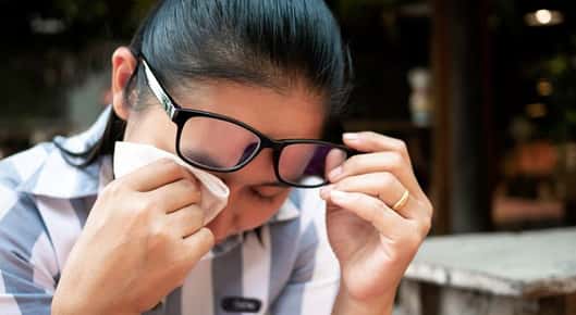 Image of a woman holding a tissue to her eye.