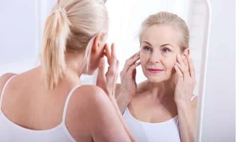 Woman examines skin in mirror