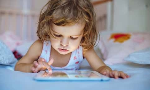 Image of a young girl who is playing on a digital tablet. 