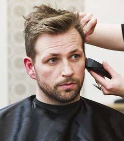 Image of someone trimming a man's beard.