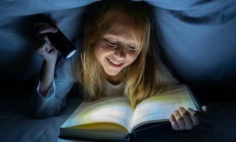 Young girl reads in the dark
