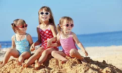 Kids protecting their eyes in sunglasses at the beach