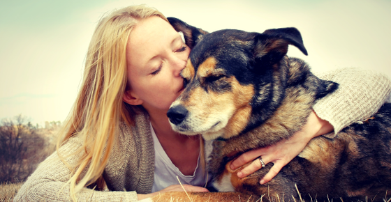 Image of a woman kissing her dog. 