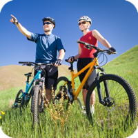 A man and woman riding their bikes on a grassy trail