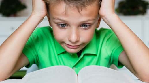 Image of a boy looking confused while reading a book.