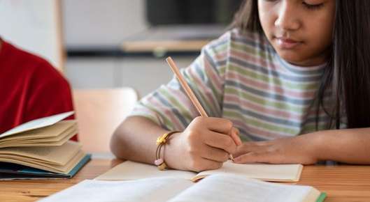 Image of a little girl smiling and writing.