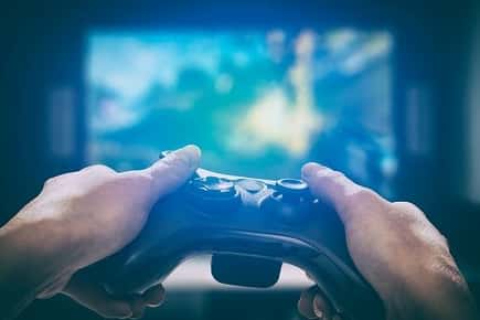 Image of a person's hands holding a controller in front of a video game screen. 