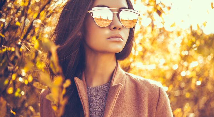 Woman wears mirrored sunglasses during fall.