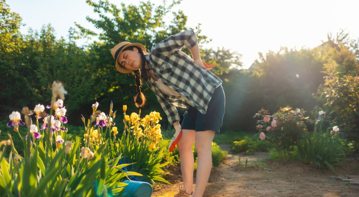 Young woman feels back pain while gardening.