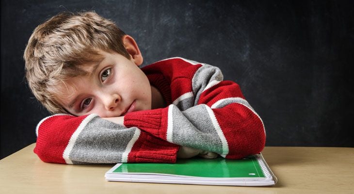 Young boy looking frustrated with book