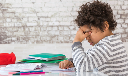 Young boy struggling to see while doing homework 