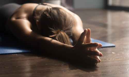 A woman practicing the face-down pose 