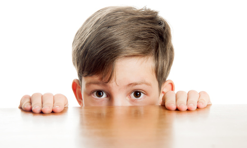 Nervous little boy peeking under table