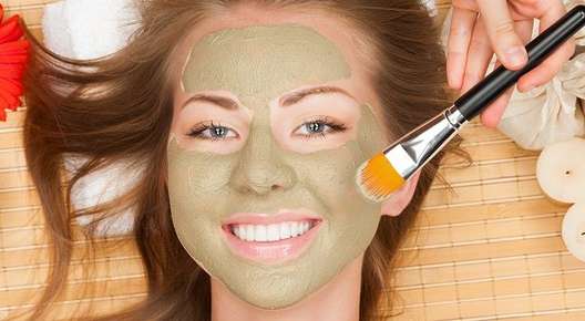 Image of a woman smiling with a facial mask.