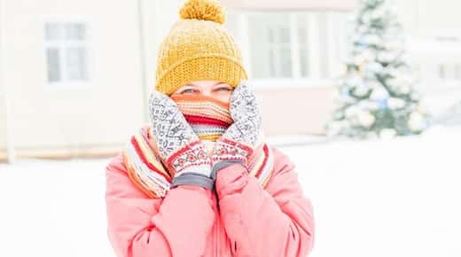 Image of a girl in the snow wearing a scarf, mittens, and a beanie.