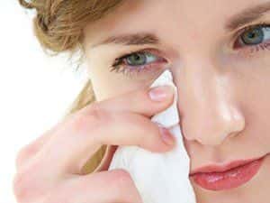 Image of a woman holding a tissue to her eye.
