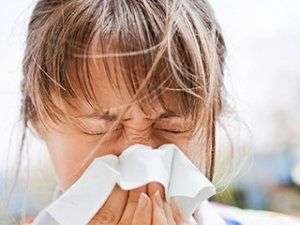 Image of a young girl blowing her nose.