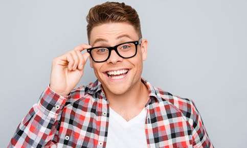 Image of a man in his early 20's, checking the fit of his trendy eyeglasses with excitement. 