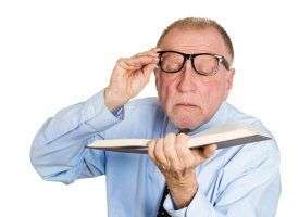 man reading with glasses pushed off face