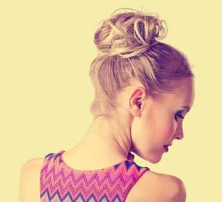 Image of the back of a woman's head with her hair tied up in a messy bun.