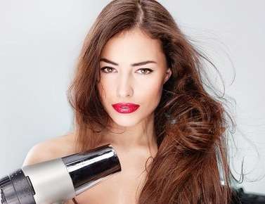 Image of a woman blowdrying her hair.