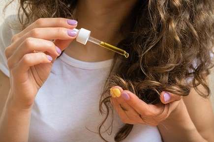 Image of oil being applied to curly hair.