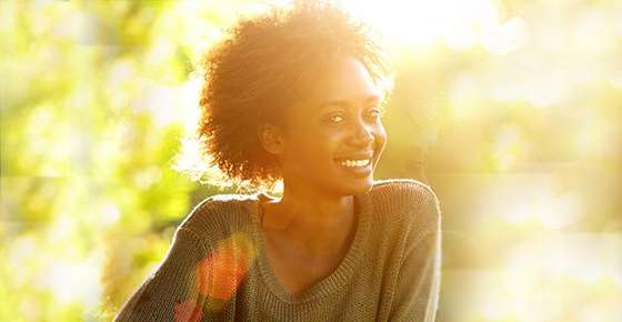 Image of a woman with natural, curly hair smiling.