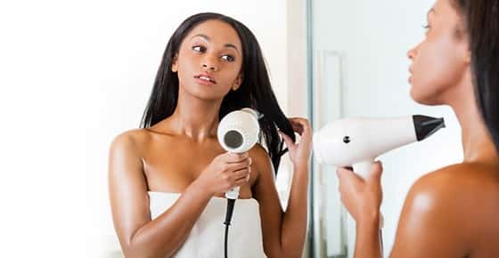 Image of a girl blow drying her hair after a shower.