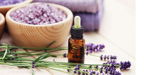 Image of an aromatherapy bottle next to flowers.