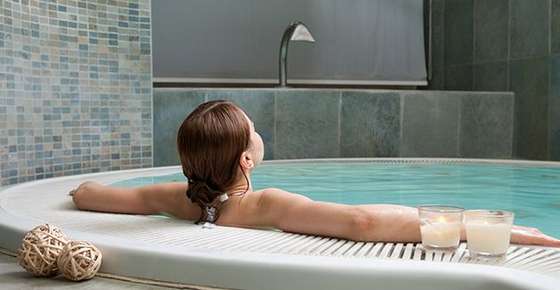 Image of a woman relaxing in a large bathtub. 