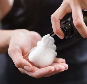 Image of hair mousse being sprayed into a hand.