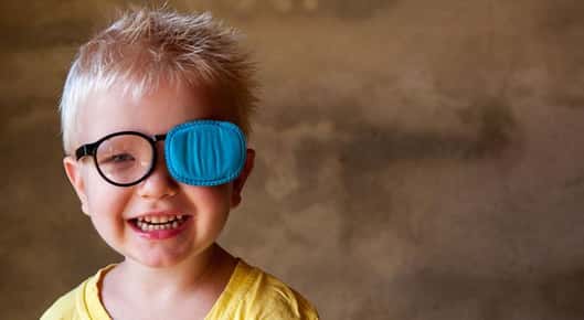 Image of a little boy wearing an eyepatch and smiling.