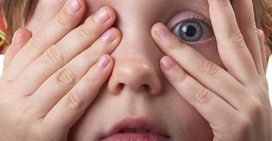 Image of a child peering out from between their fingers. 