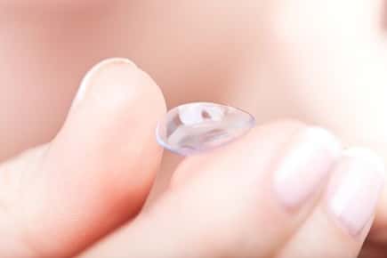 Image of hand holding a contact lens. 