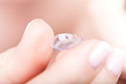 Image of hand holding a contact lens. 