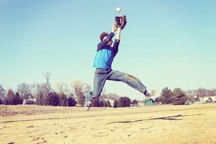 Image of a boy catching a baseball. 