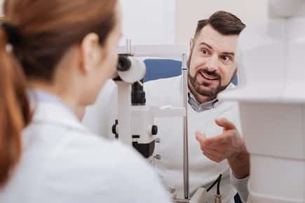 Image of a male patient asking his eye doctor questions during an exam.