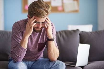 Image of man with a headache who is placing his hands on the side of his head to help ease the discomfort. 