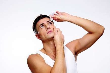 Image of guy using eye drops.