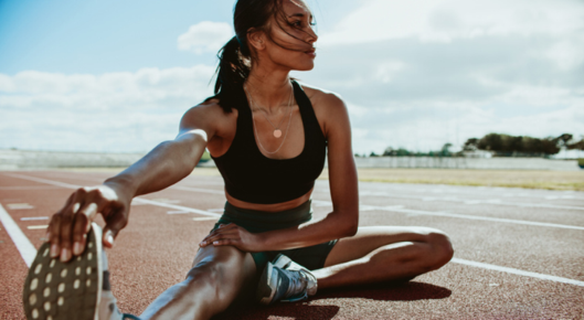 Woman stretches on a track field.