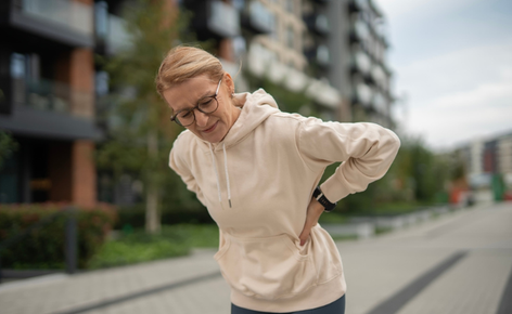 Old woman has back pain while walking.