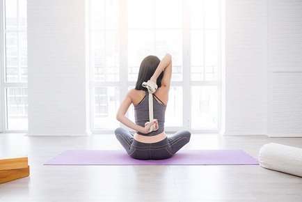 Image of a woman doing yoga with a stap. 