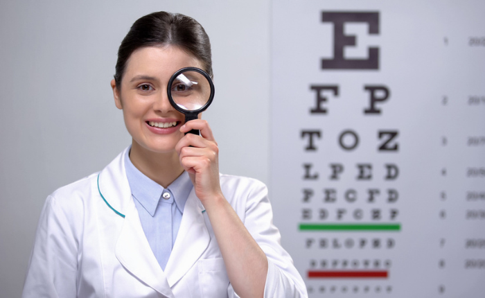 Woman optometrist watches you through a looking glass.