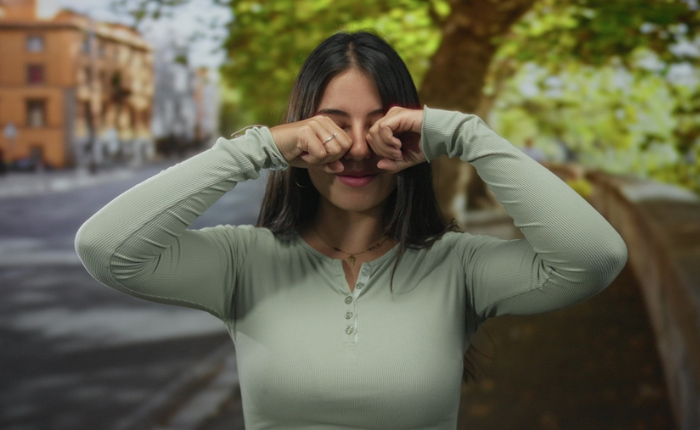 Woman rubs her eyes for the camera.