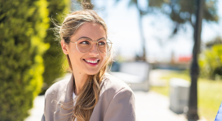 Pretty woman wearing glasses smiles over her shoulder.